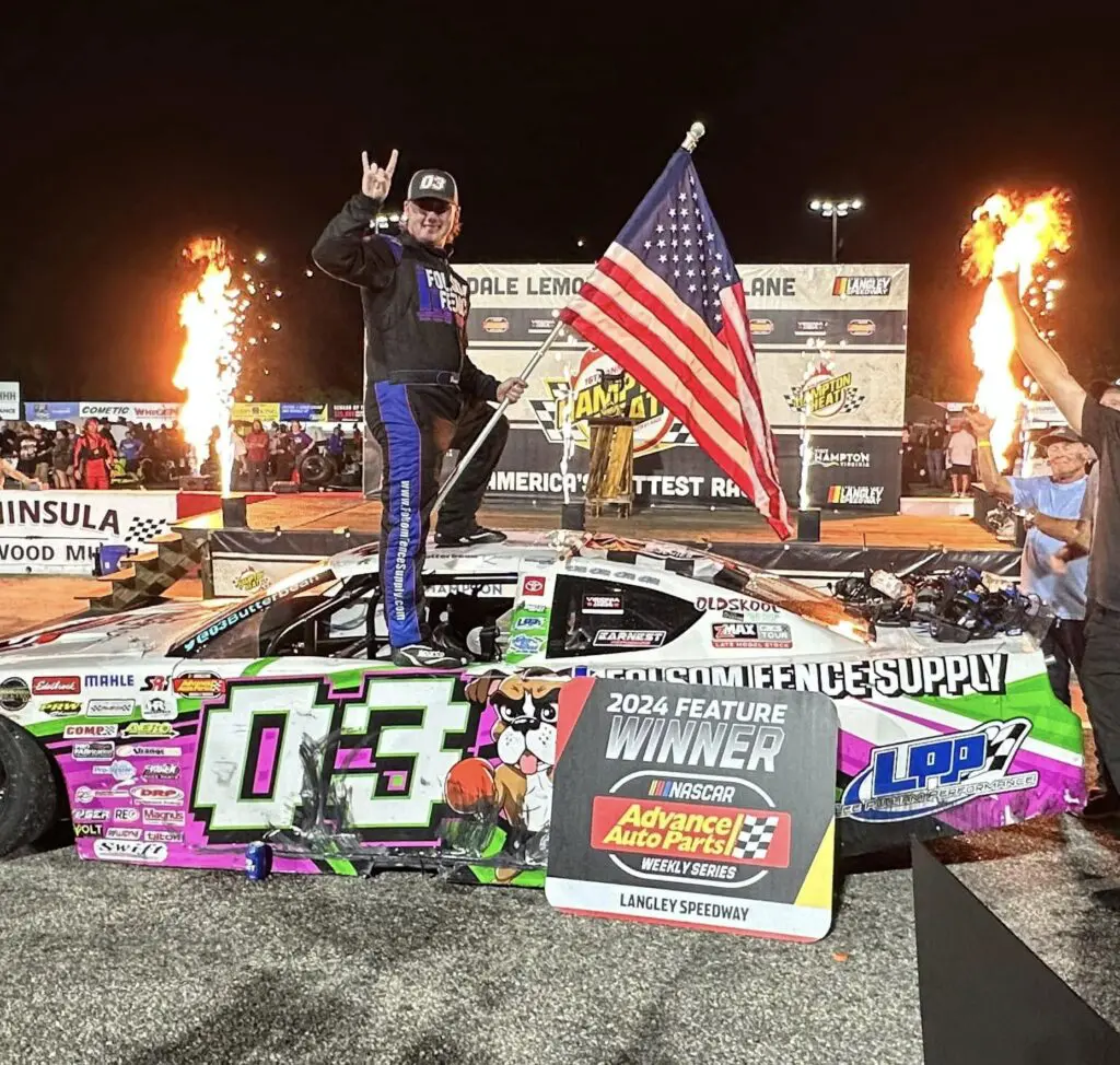 Driver stands on car holding American flag