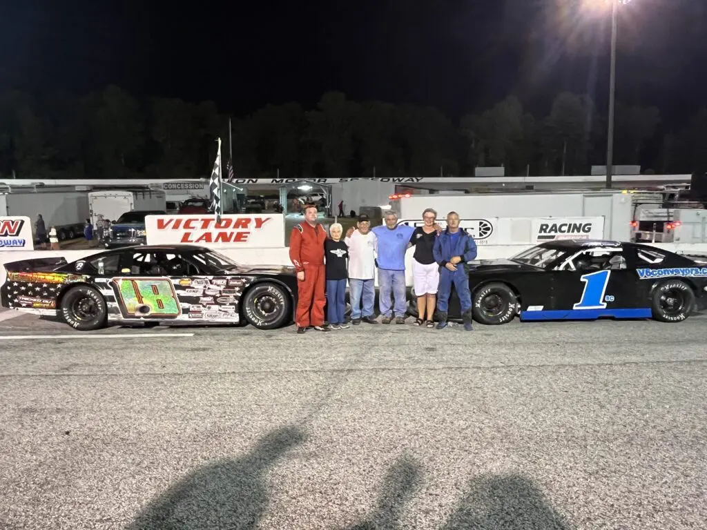 Race cars with group in victory lane