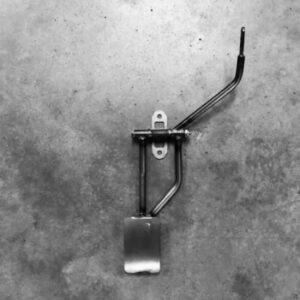 A metal pedal on the ground in black and white.