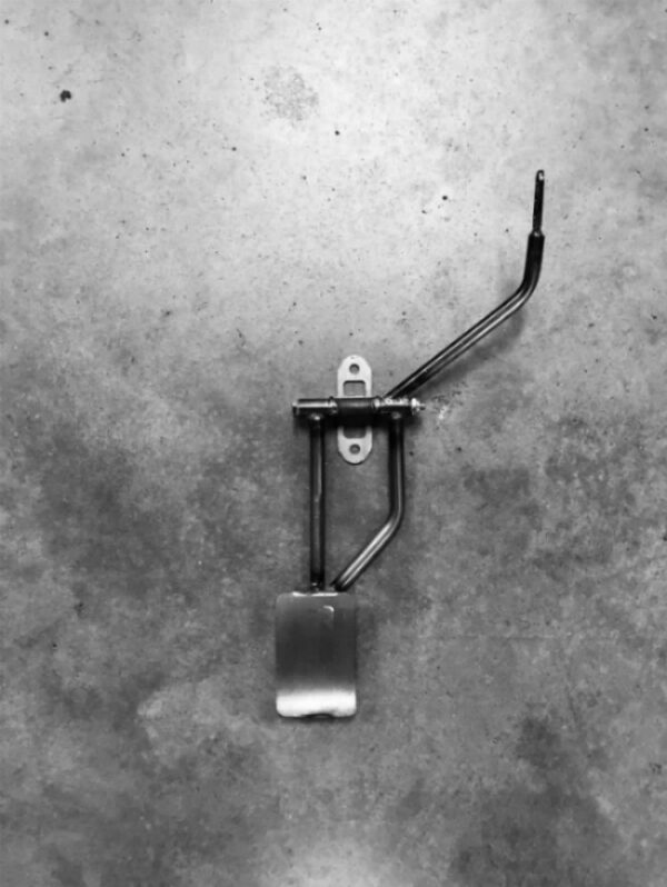 A metal pedal on the ground in black and white.