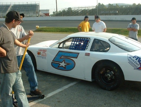 A group of people standing around a white race car.