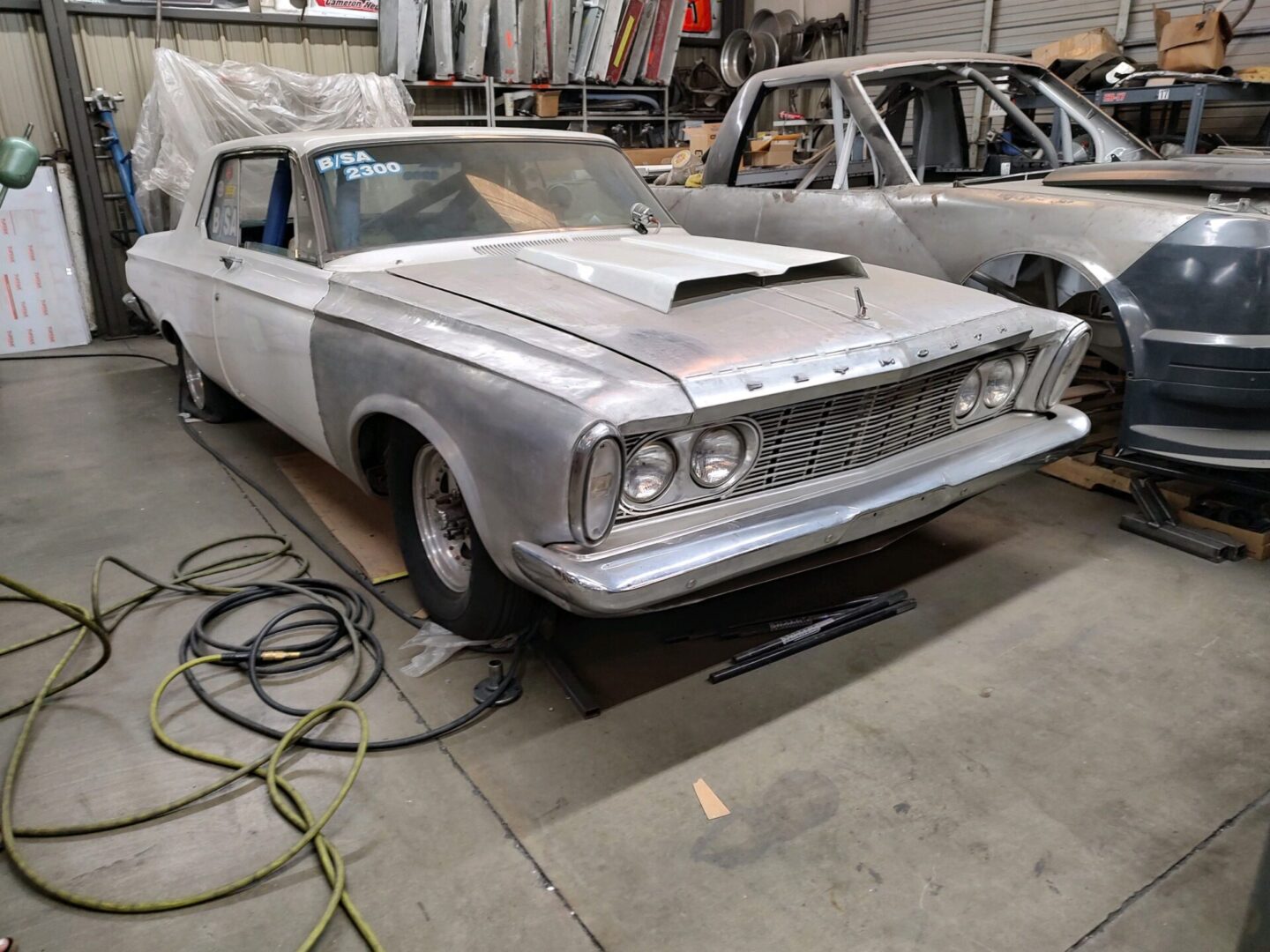 A silver car parked in a garage next to other cars.