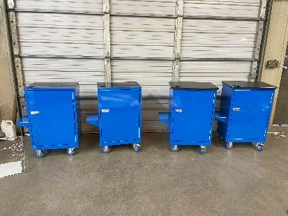 A group of four blue carts in front of a wall.