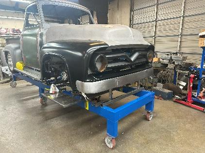 A black truck is being worked on in the garage.