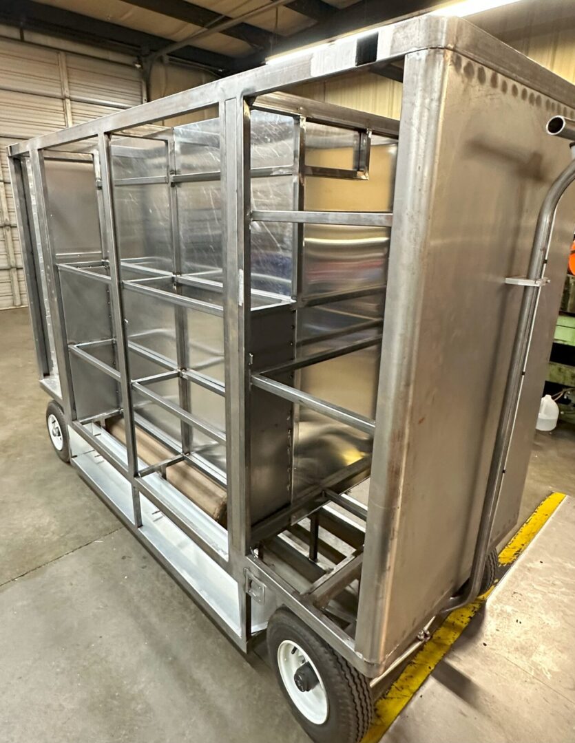 A metal cart with shelves and wheels in it.