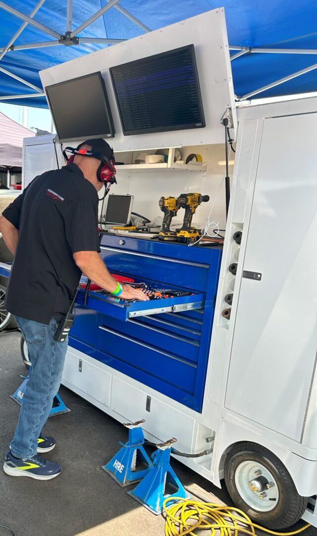 A man standing next to a truck with tools in the back.