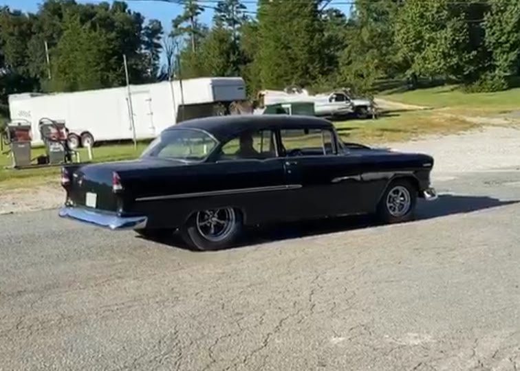 A black car parked in the middle of a parking lot.